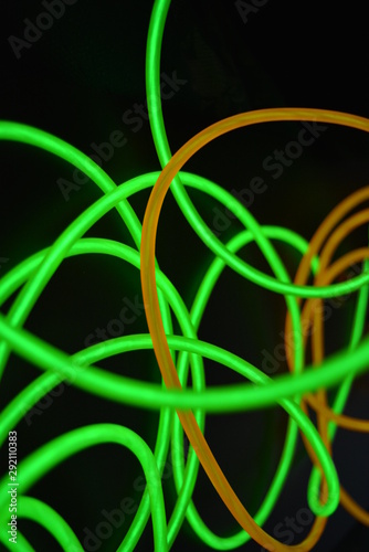 Bright luminous yellow and green, lime neon wires in different formats and layouts. An electroluminescent wire, a neon light guide, an ice tube are folded into different structures and shapes.