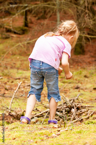 Little girl alone searching wood and food in the forest