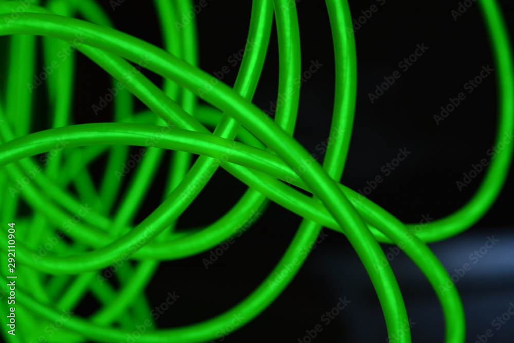 Toxic green luminous wires with different shapes and structures. A web of lime fiber and unusual circles located on a black glossy surface. Toxic green luminous wires with different shapes and structures. A web of lime fiber and unusual circles located on a black glossy surface.