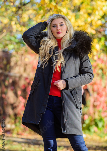Girl in warm coat stand in park nature background defocused. Woman long blonde hair wear stylish outfit with parka. Create fall outfit to feel comfortable and pretty. Modern outfit for youth