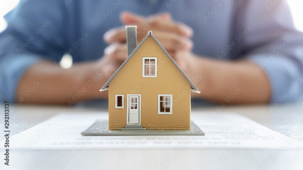 House model with agent and customer discussing for contract to buy, get insurance or loan real estate or property background. House model with agent and customer discussing for contract to buy, get insurance or loan real estate or property background.