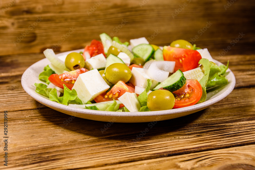 Ceramic plate with greek salad on wooden table