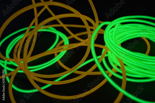 Bright luminous yellow and green, lime neon wires in different formats and layouts. An electroluminescent wire, a neon light guide, an ice tube are folded into different structures and shapes.