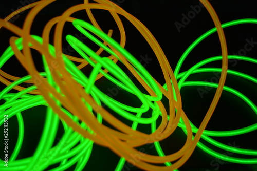 Bright luminous yellow and green  lime neon wires in different formats and layouts. An electroluminescent wire  a neon light guide  an ice tube are folded into different structures and shapes.