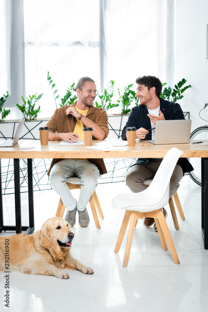 two handsome friends smiling and looking at each other two handsome friends smiling and looking at each other