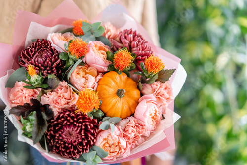 Autumn bouquet of mixed flowers in womans hands. The work of the florist at a flower shop. Fresh cut flower. photo