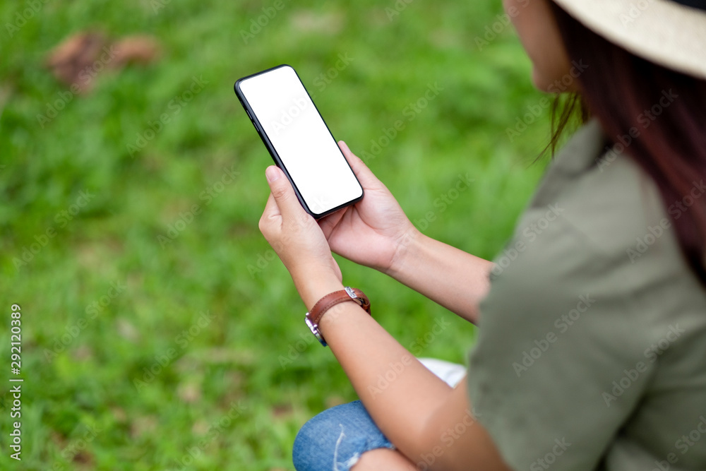 Mockup image of a woman holding black mobile phone with blank desktop screen in the park