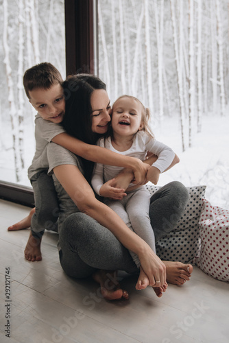 The family is sitting at the window and looking at the winter forest. Good New Year spirit. Morning in pajamas.