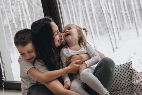 The family is sitting at the window and looking at the winter forest. Good New Year spirit. Morning in pajamas. © malysheva