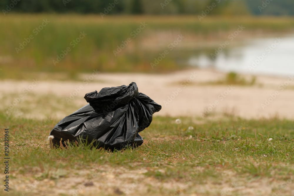 Black packet with garbage on countryside lake Black packet with garbage on countryside lake