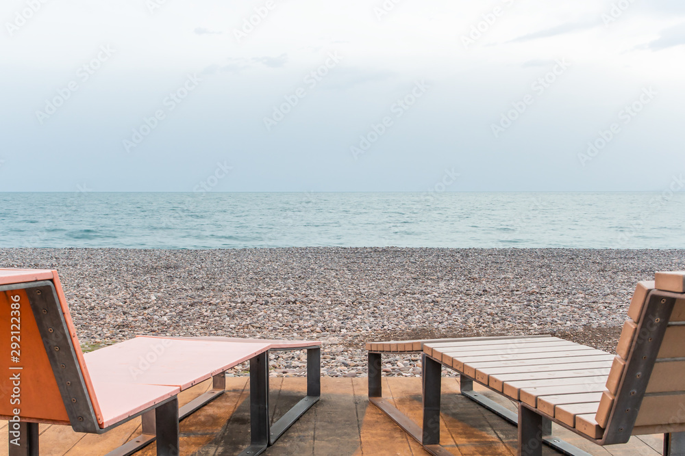 Low angle view of deck chairs on a pebble beach - obrazy, fototapety, plakaty 