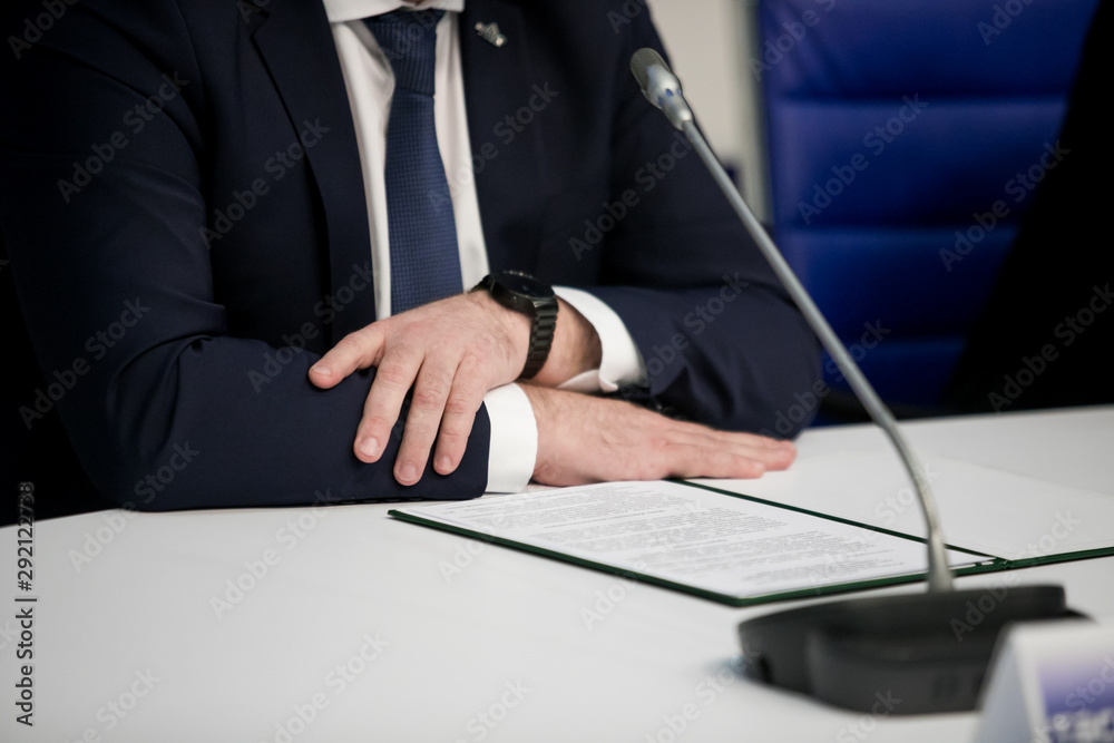 Obraz premium Close-up of participants of press conference sitting at the table in a row in front of audience