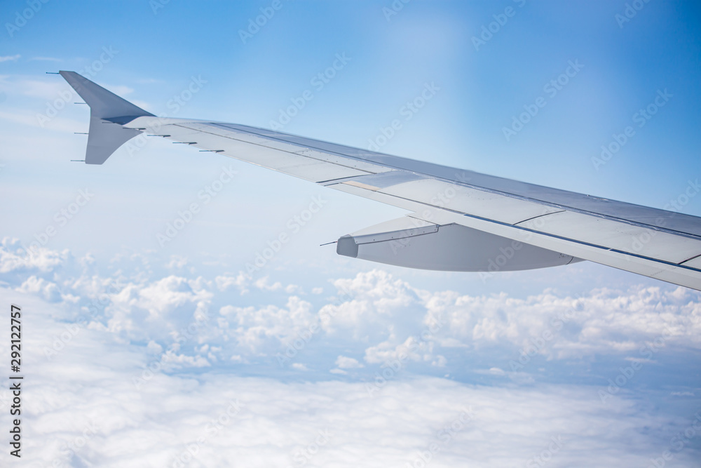 Fototapeta premium wing of airplane over cloudy blue sky in Europe on morning sun light, 