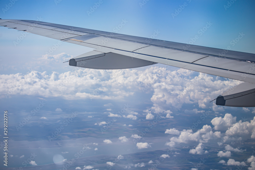 Obraz premium wing of airplane over cloudy blue sky in Europe on morning sun light, 