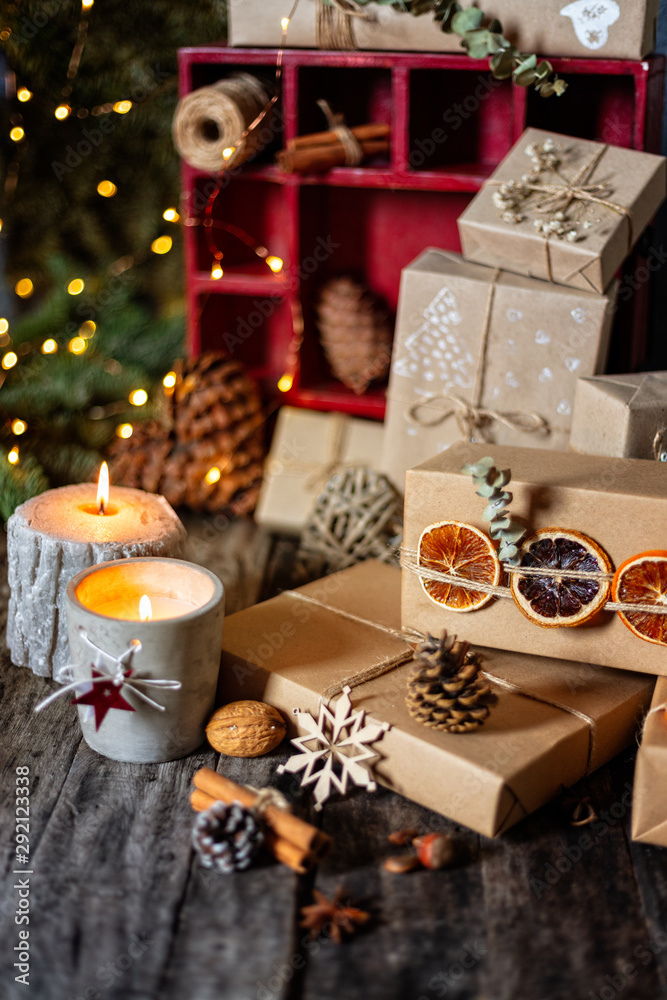 Christmas arrangement with presents, wrapped gifts, candles, festive decorations and Christmas tree with light on background, vertical composition