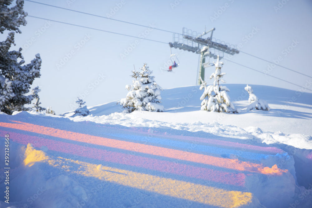 Multicoloured reflections on the snow and skiing lift behind them Multicoloured reflections on the snow and skiing lift behind them