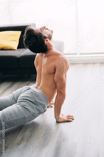 Man Practicing Yoga At Home Doing Sun Salutation Routine