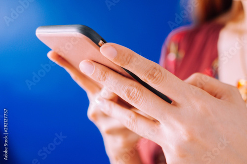 A young woman is using a mobile phone on a blue background