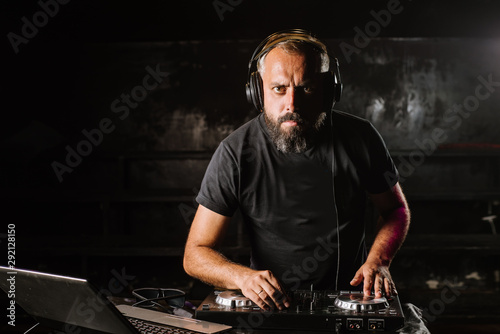 DJ plays on a mixer in the club on black background