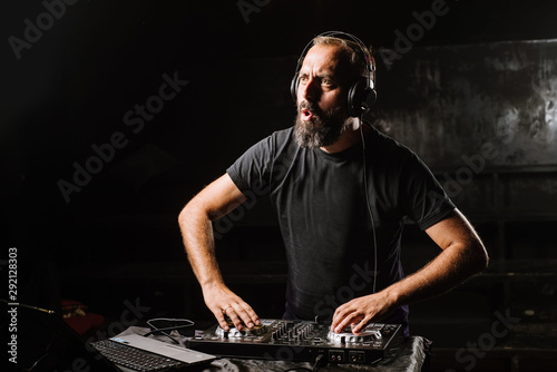 DJ plays on a mixer in the club on black background