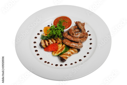 Grilled sausages with zucchini and sauce on a plate on a white isolated background