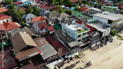 Fisherman village on seashore. Aerial view of typical touristic place on Ko Samui island with souvenir shops and walking street on sunny day. Architecture in asia, local settlement drone view. photo