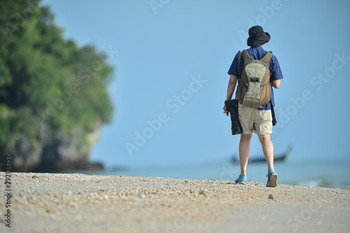 The tourist walking on the white beach with camera