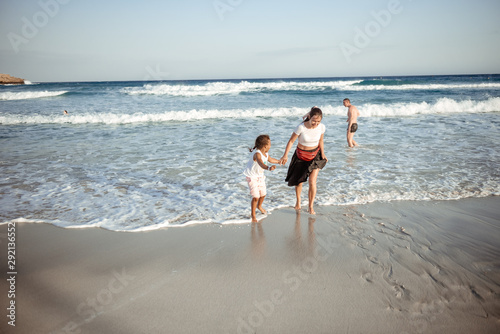 Family walking on the evening beach during sunset. Child with mom.