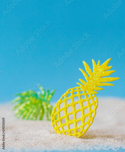 Close-up of bright yellow lace pineapple and green leaves on the sand beach.