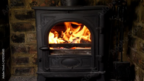 4K Loaded wood burning stove with logs in, lit fire heating British home with flames