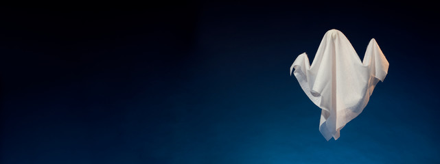 Image of halloween ghosts made of white fabric on empty dark blue background