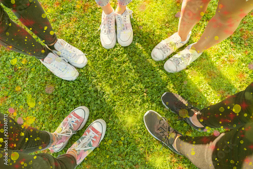 Top view Image of shoes of young teenagers girls standing in a circle on the grass of a park. Enjoying a happy moment  Having fun and enjoying their friendship. Concept of unity and diversity.