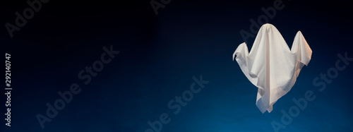Image of halloween ghosts made of white fabric on empty dark blue background