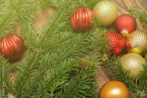 Fur spruce pine coniferous branches  sparkling shiny toys balls on the brown brushed wooden background