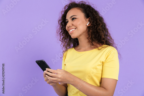 Image of joyful african american woman listening to music with earpods