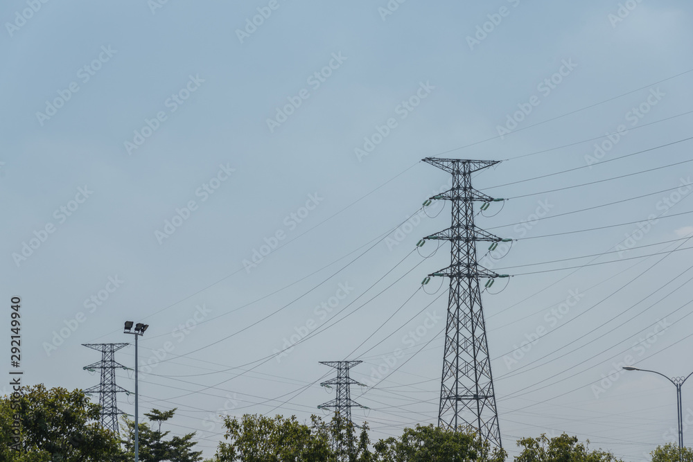 High voltage tower network stands in the woods in the blue sky background