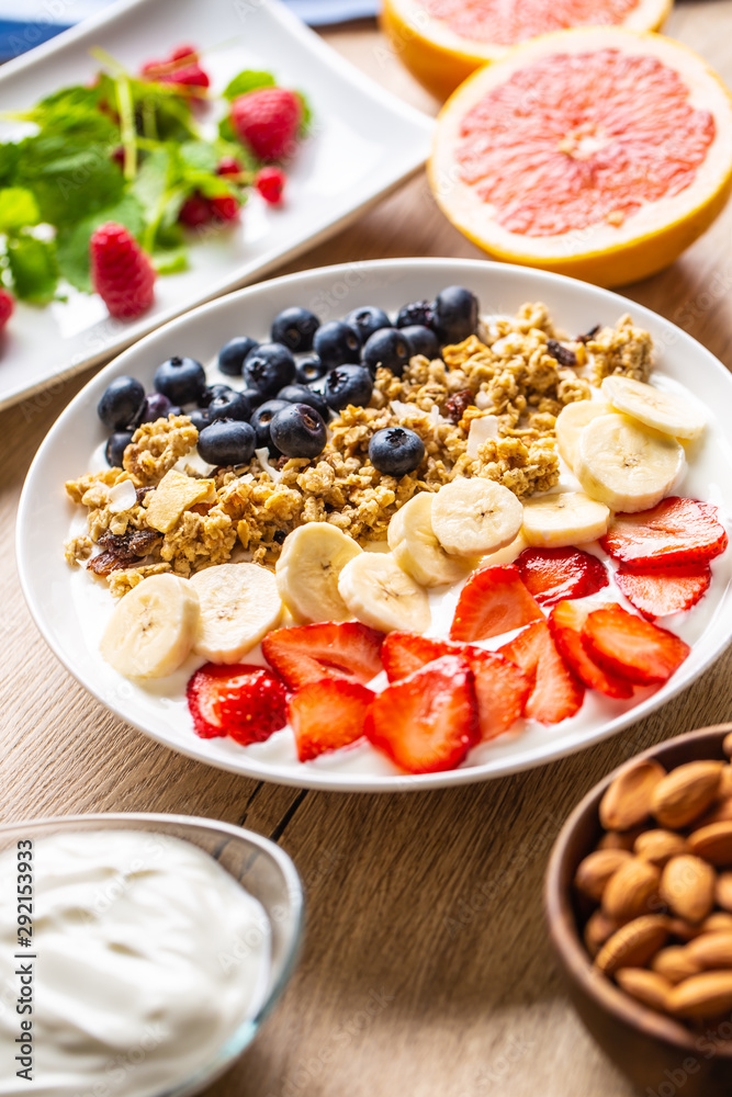 Healthy breakfast served with plate of yogurt muesli blueberries strawberries and banana. Healthy breakfast served with plate of yogurt muesli blueberries strawberries and banana.