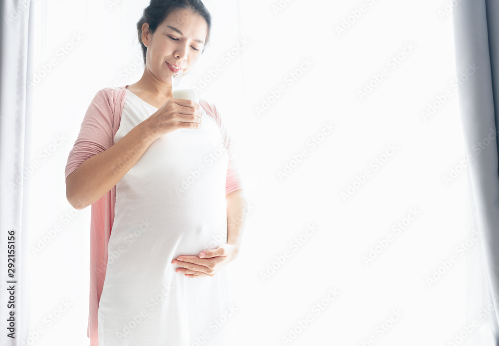Pregnant woman touching belly and holding a glass of milk intront of drapery for love and expecting baby to healthy. Pregnant woman touching belly and holding a glass of milk intront of drapery for love and expecting baby to healthy.