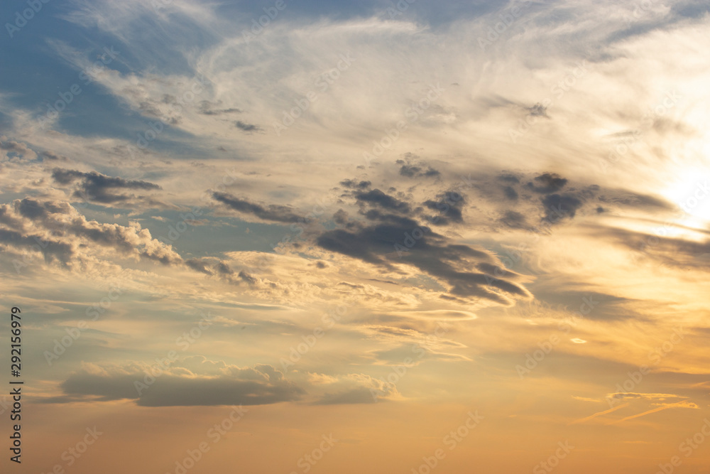 Cirrus clouds at sunset, beautiful sky with blue orange yellow clouds. Dramatic heaven evening twilight sunbeams