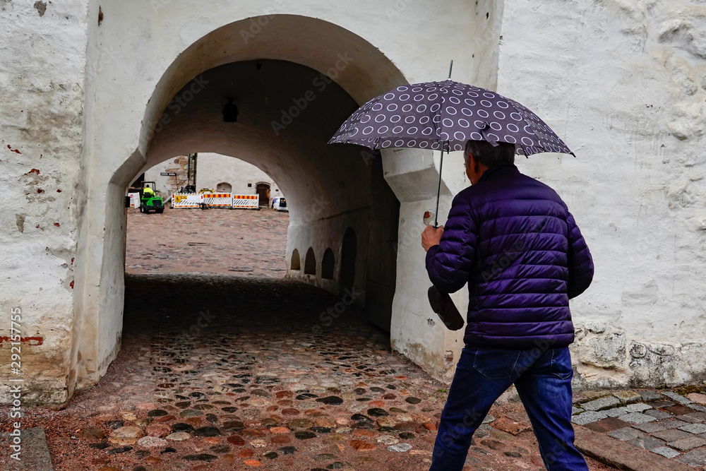 Turku, Finland A man with umbrella enters the main vaulted gate at the 13th century medieval Turku Castle