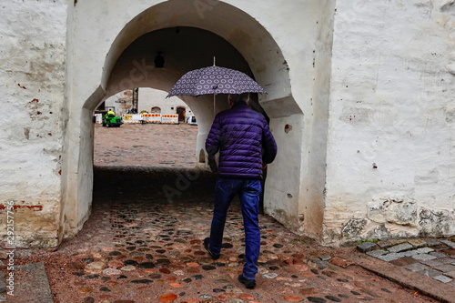 Turku, Finland A man with umbrella enters the main vaulted gate at the 13th century medieval Turku Castle © Alexander