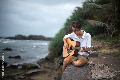 Romantic young man with a guitar on the beach