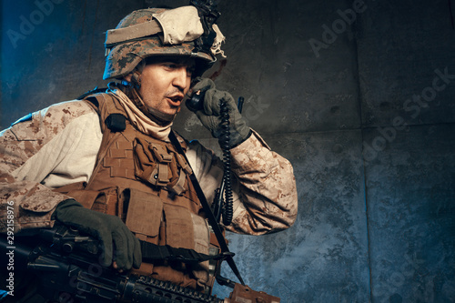 Young man in military outfit a mercenary soldier in modern times on a dark background in studio