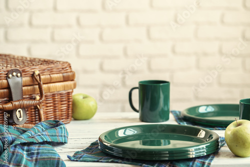 Wooden basket for picnic with plates, cups and silverware close up