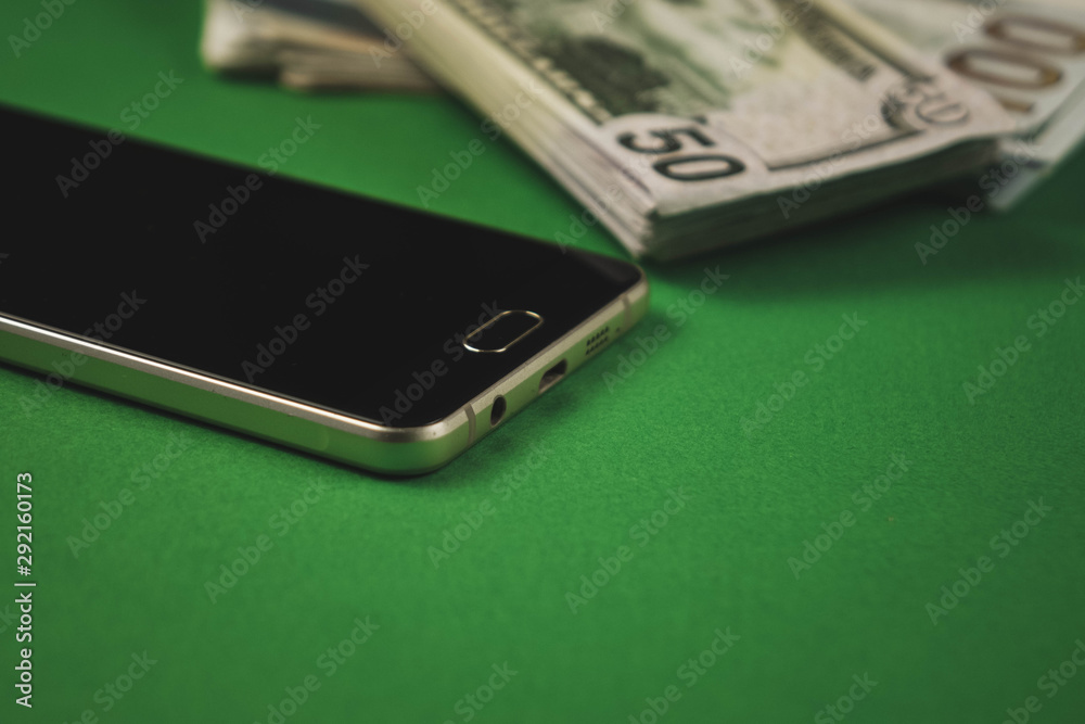 many packs of cash and phone lying on a green background many packs of cash and phone lying on a green background