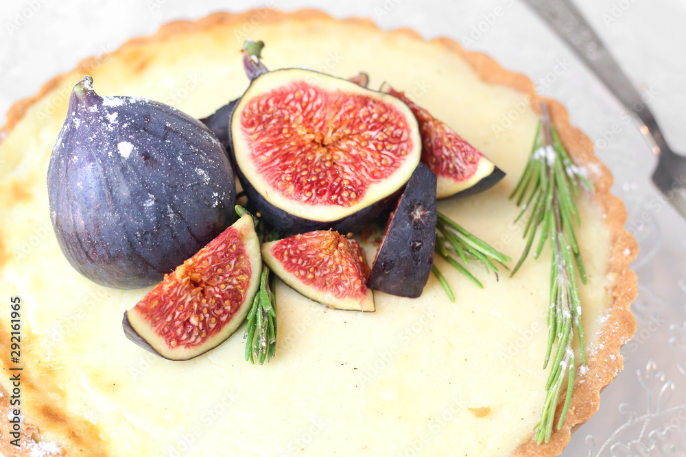 gorgeous round french classic homemade shortcake pastry dough vanilla custard tart cake decorated with figs and rosemary on glass stand near with retro fork on grey table cloth. Insta food photo style gorgeous round french classic homemade shortcake pastry dough vanilla custard tart cake decorated with figs and rosemary on glass stand near with retro fork on grey table cloth. Insta food photo style