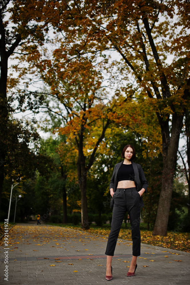 A tall leggy young beautiful and elegant model woman at formal wear posed at autumn background. A tall leggy young beautiful and elegant model woman at formal wear posed at autumn background.