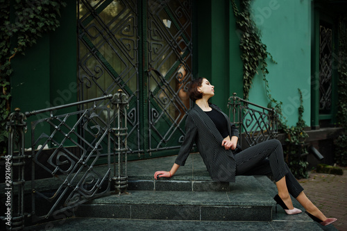 A tall leggy young beautiful and elegant model woman at formal wear posed on stairs.