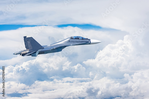 Combat fighter jet flies high in the clouds.