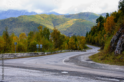 A curving autumn road with colorful forest and mountain in the far distance